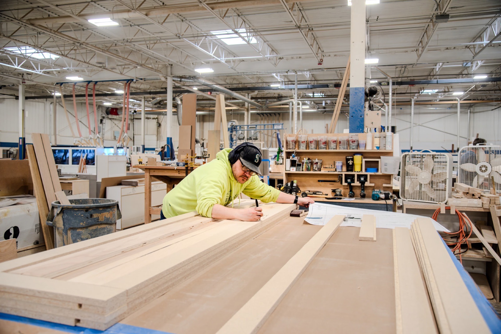 Bench carpenter laying out a panel from shop drawings on the floor
