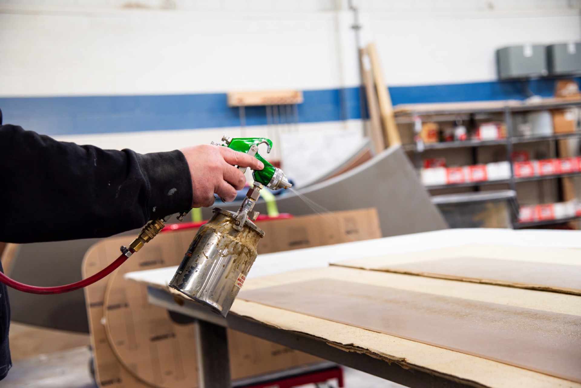 Finisher applying a clear top coat with a spray gun in the climate-controlled booth